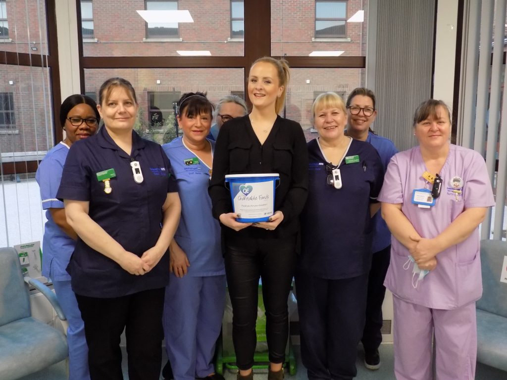A picture of Kathryn and the nursing team at the chemo day unit, receiving Kathryn's donation.