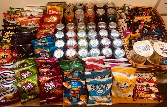 A picture of Kathryn's tuck shop at her office, including crisps, cans of pop and chocolate.