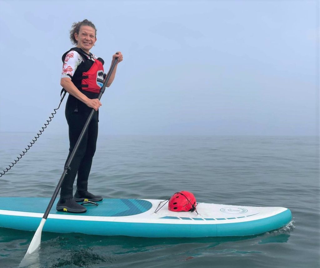 A picture of Fior standing on top of a kayak in the sea.