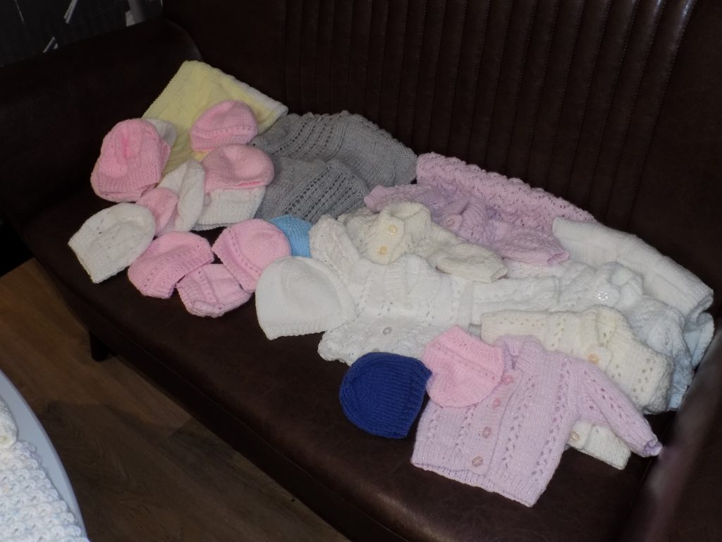 A picture of the knitted donations laid out on a settee.
