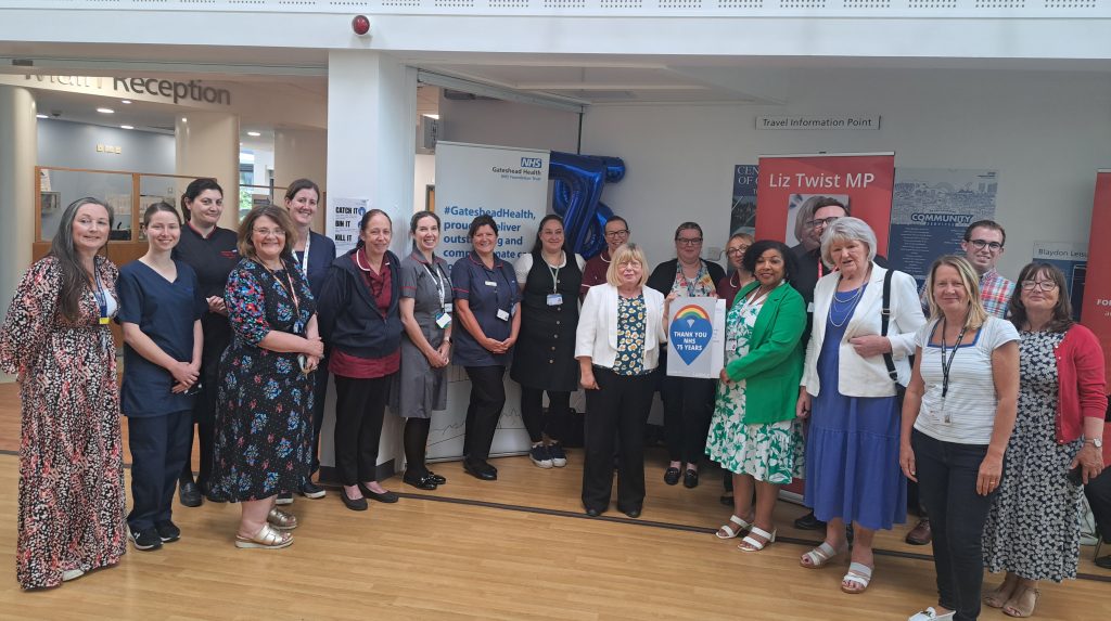 Large group of staff with local MP, councillors and residents celebrating NHS75