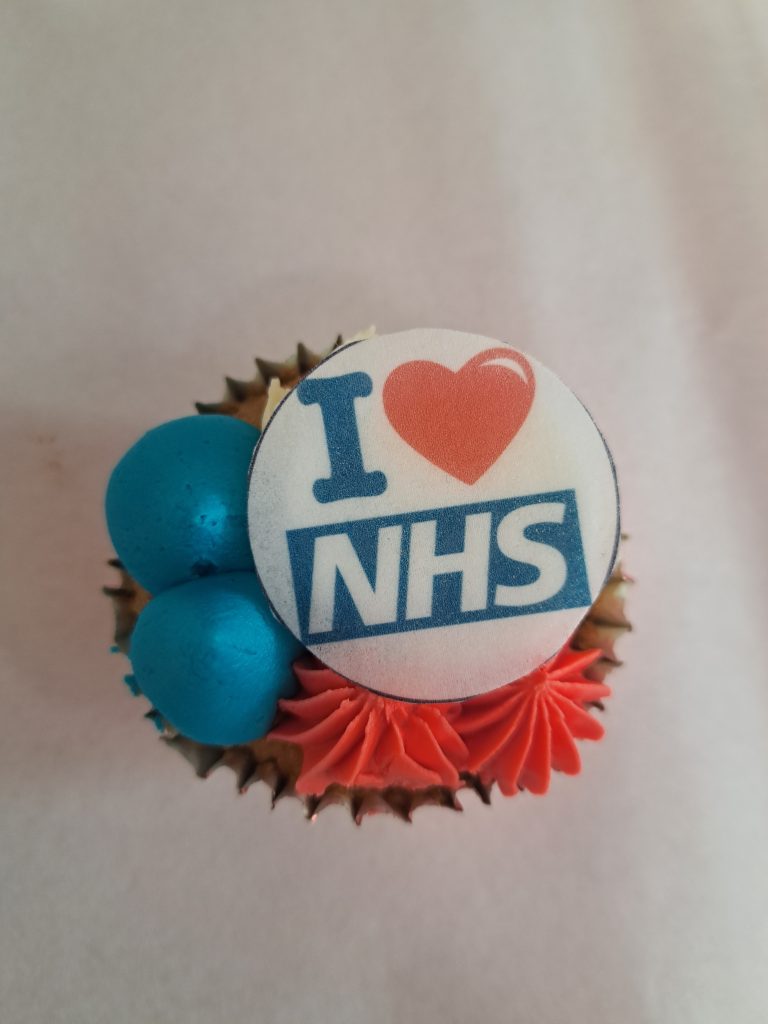 A cup cake with a label reading "I heart NHS"