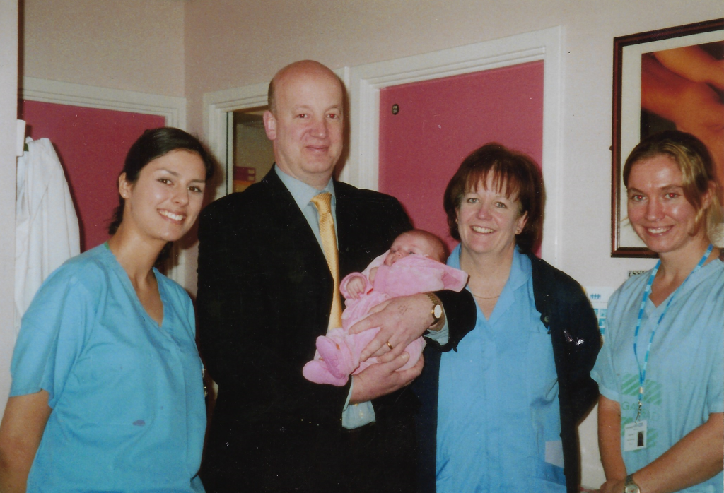 Ian Aird holding a baby, three members of the IVF team.