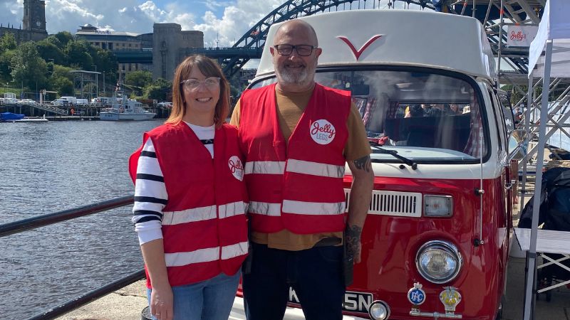 two people stood in front of a red van