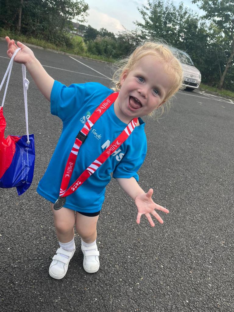 little girl runner with medal doing a pose in carpark