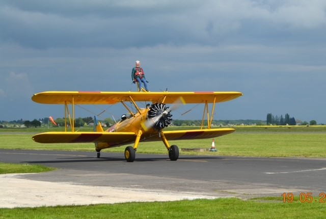 Brenda sat on top of a yellow plane about to take off