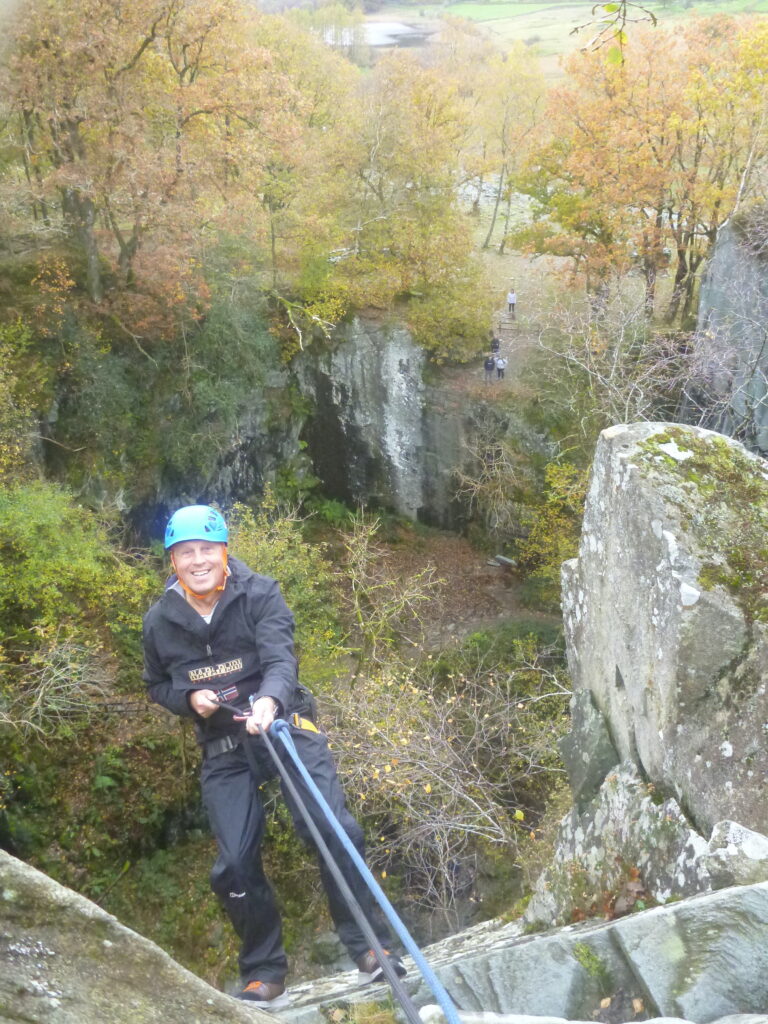 photo of a man in climbing gear abseiling down a cliff face