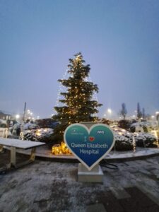 A photo of a lit up festive tree with a heart in front reading "I love Queen Elizabeth Hospital"