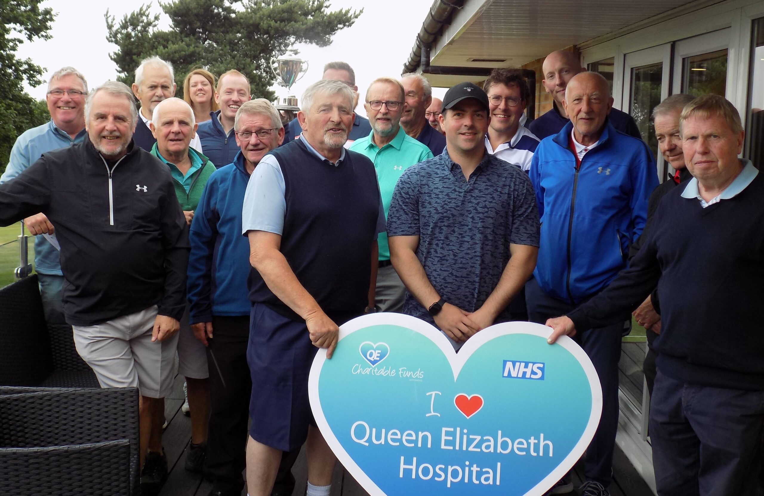 A picture of everyone that took part in the golf event, standing on the balcony of the golf club.