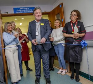 Photo of a group of staff and patients at the official opening with Sir Paul Ennals cutting the ribbon