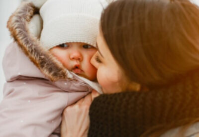 A mother keeping her baby warm outside in winter