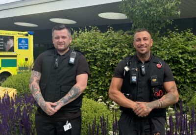 Two members of security staff standing outside a hospital entrance.