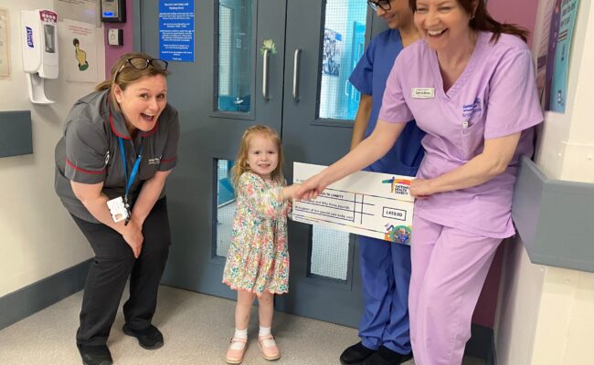 Rosie donating the money that she had raised to the children's unit department