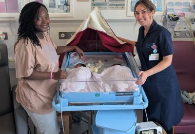 Photo of a midwife with a new mum and twin babies.