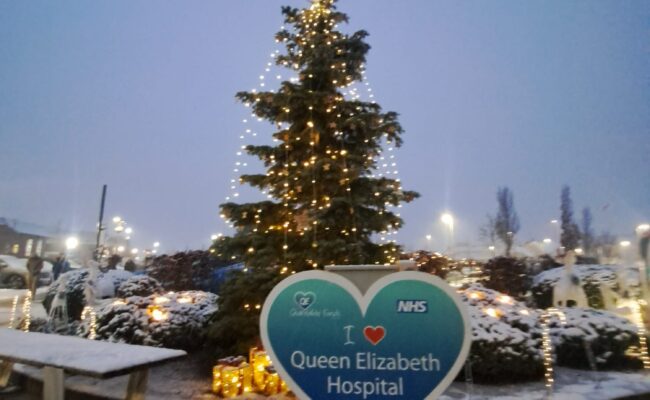 A photo of a lit up festive tree with a heart in front reading "I love Queen Elizabeth Hospital"