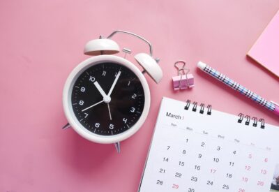 Alarm clock and calendar on a pink background