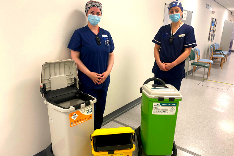 Two nurses against a white background with recycling bins for sustainability