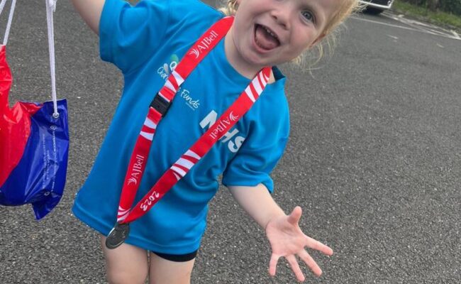 little girl runner with medal doing a pose in carpark